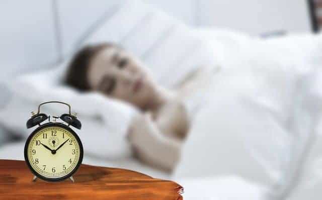  μια γυναίκα που κοιμάται με ένα ξυπνητήρι δίπλα στο κρεβάτι της