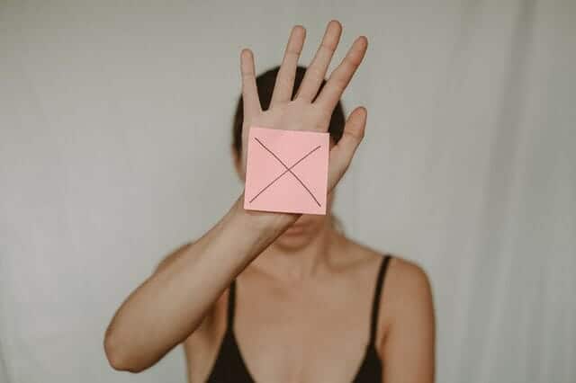 μια θλιμμένη γυναίκα κρατάει ένα χαρτόκουτο με ένα x μπροστά της