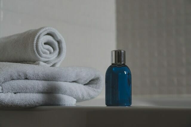  μπλε μπουκάλι με σαμπουάν, πετσέτες δίπλα του