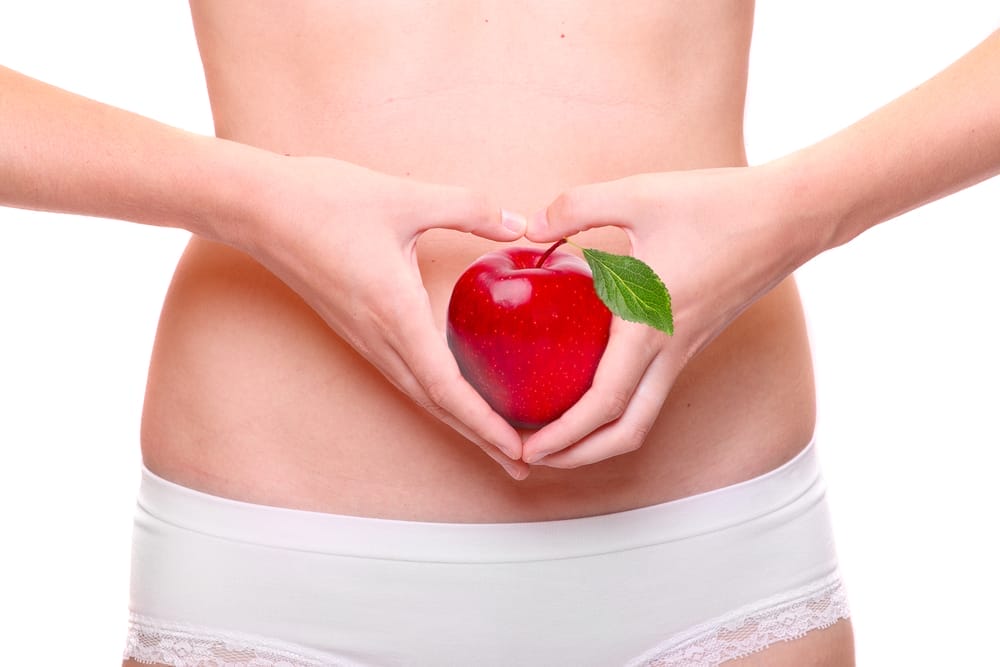  μια γυναίκα κρατάει ένα μήλο στο στομάχι της